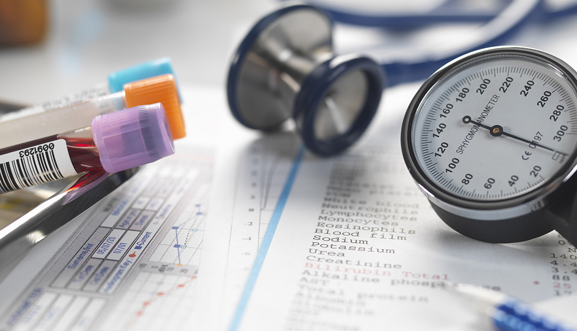 A doctor's desk filled with patient test results, samples, stethoscope and blood pressure gauge