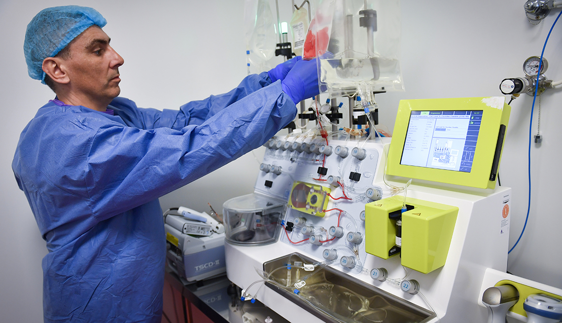 A lab technician handles an automated device used for cell processing