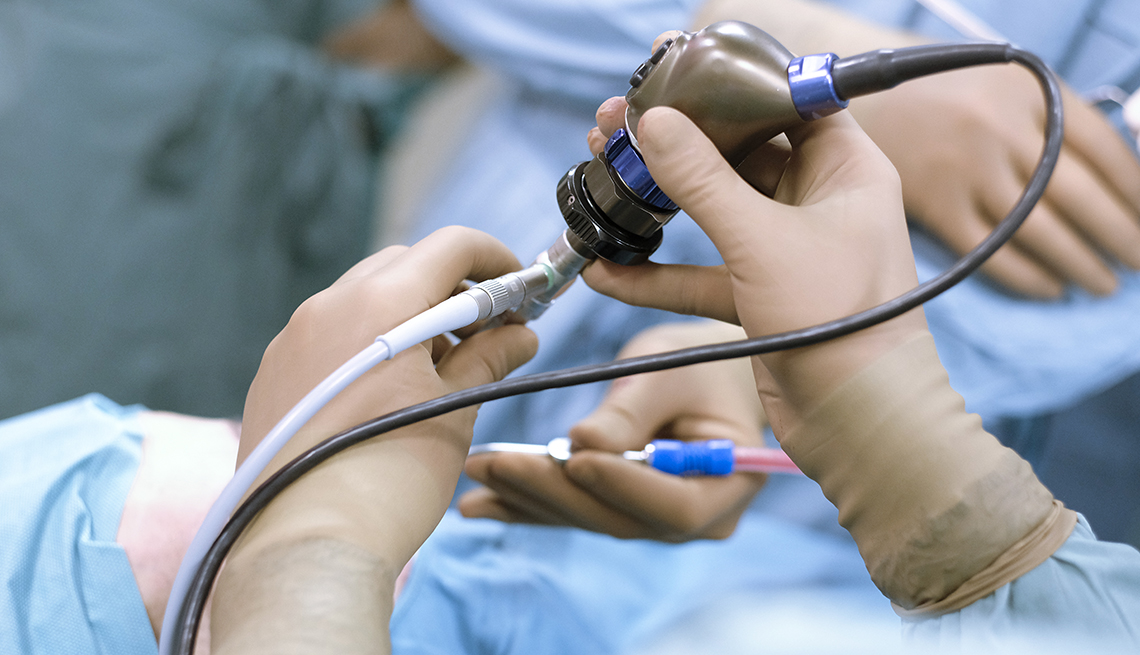 surgeon and nurse hands holding endoscopic scope over patient on operating table during a procedure