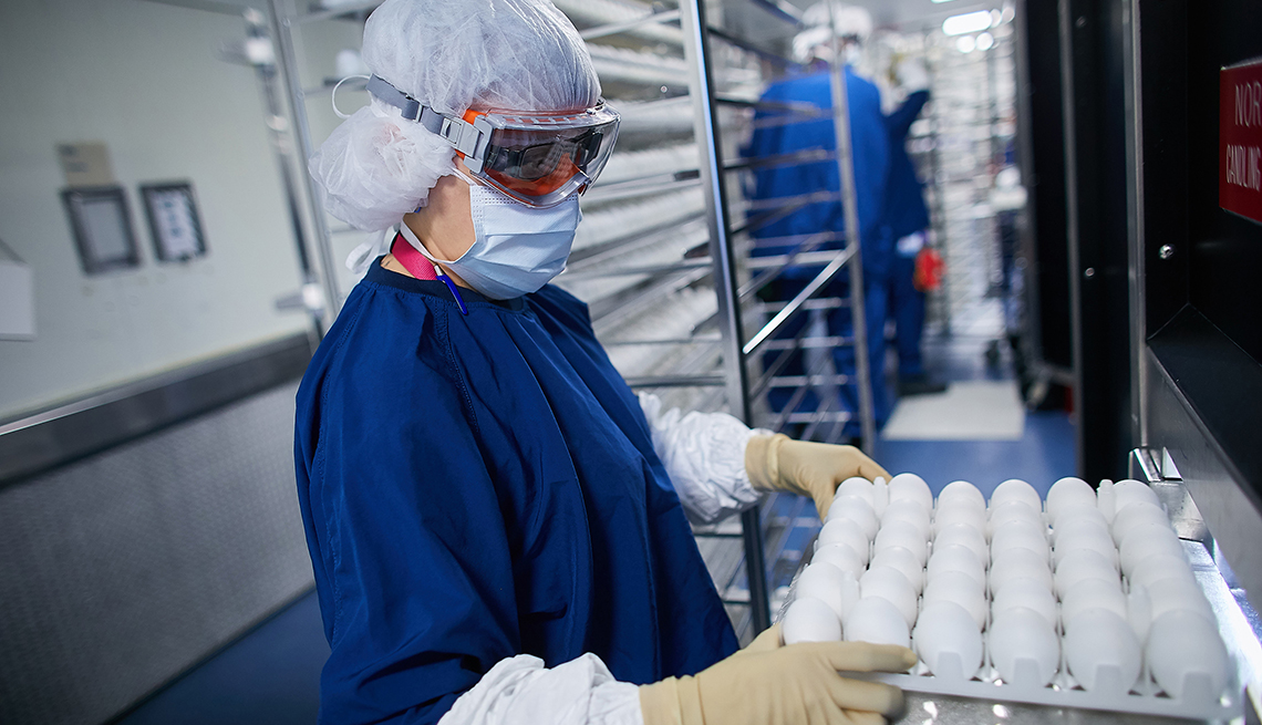 Un científico lleva huevos que se cosechan para la vacuna contra la gripe