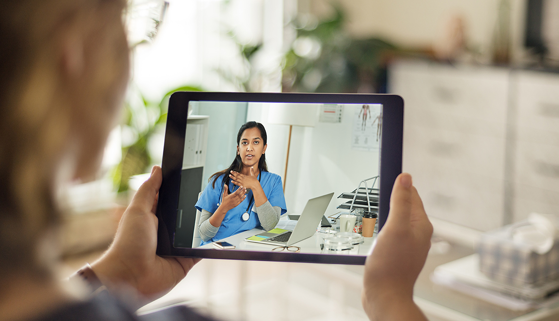 A patient talks to a doctor by videoconferencing using a digital tablet