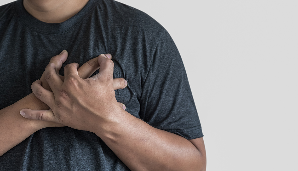 A man places his hands on his chest suffering from apparent pain from his heart