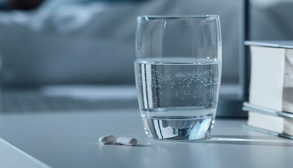 water glass and pills on bedside table