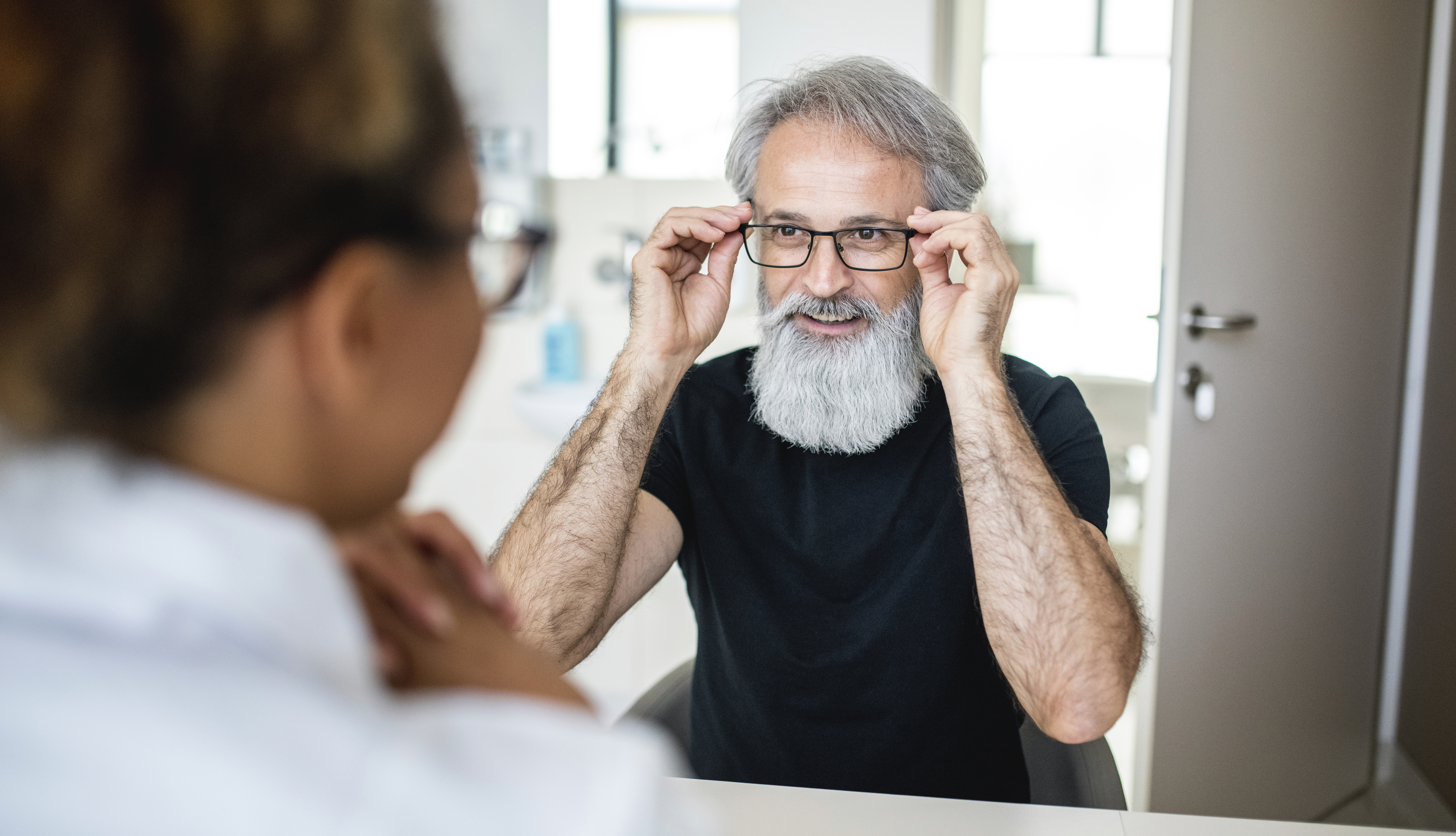 man at optometrist office trying on new glasses