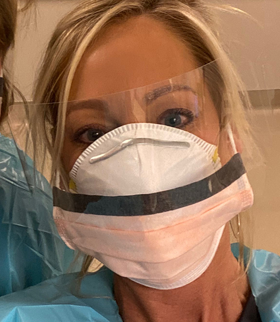 closeup selfie of a nurse wearing a mask and face shield personal protective gear