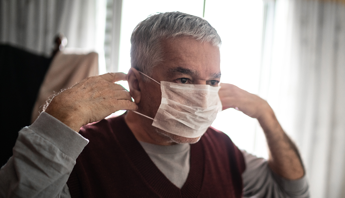man putting on a protective mask for coronavirus at home