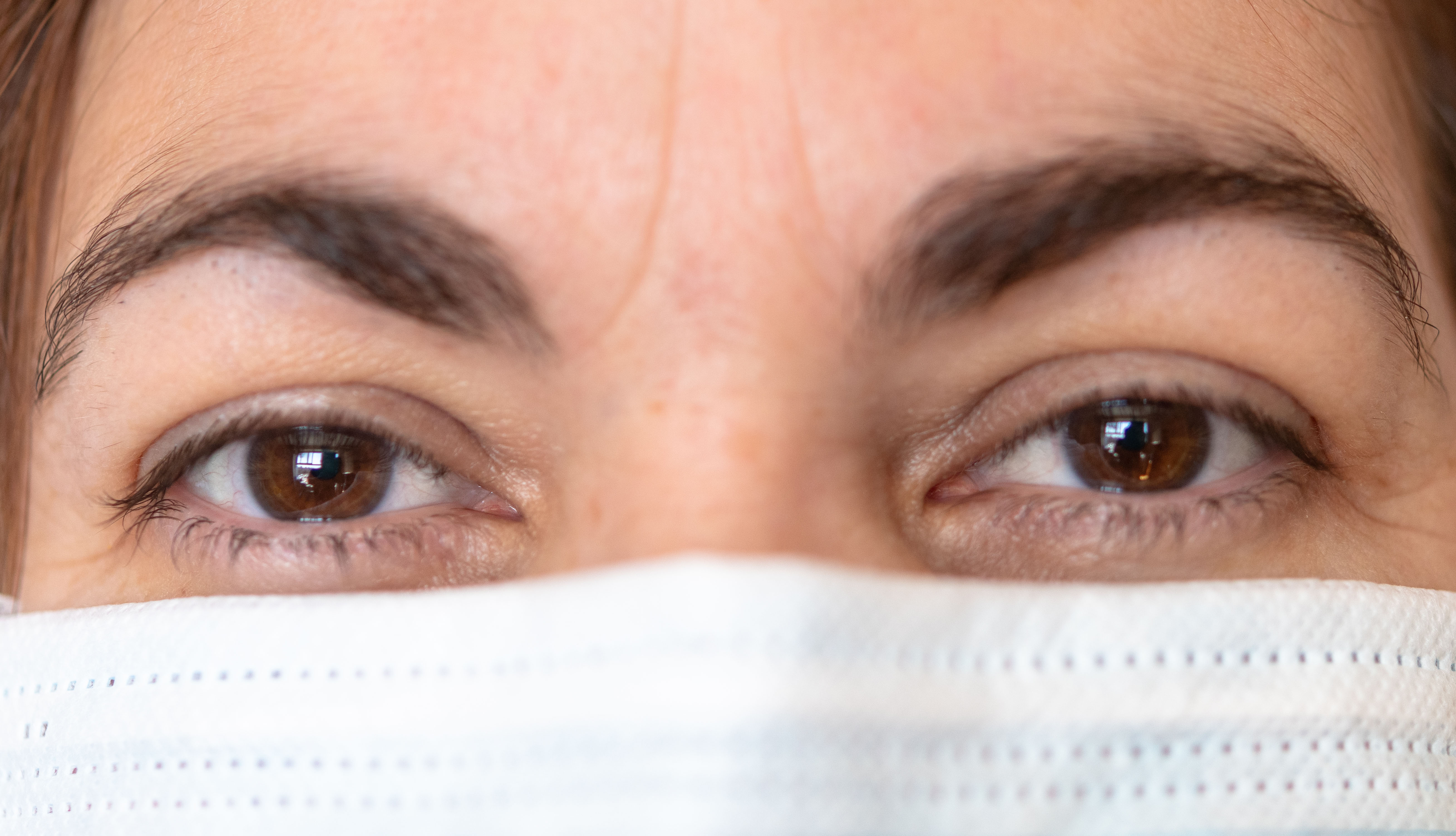 close up of a woman's eyes and nose and she is wearing a face mask