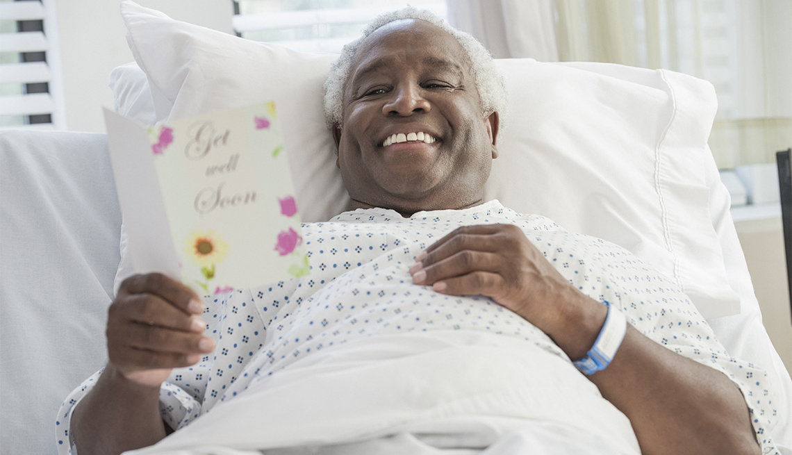 man reading get well soon card in hospital bed