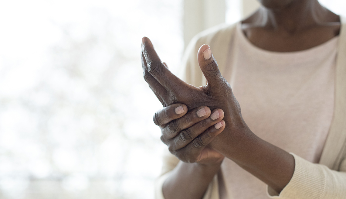 Una mujer se masajea sus manos para aliviar el dolor de la artritis