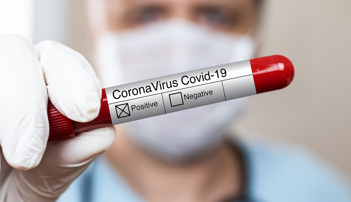 Empleado de laboratorio sostiene una muestra de sangre que dice coronavirus COVID 19