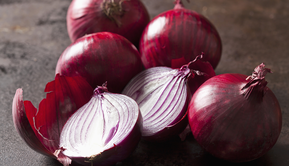 Close up of whole and sliced red onions.