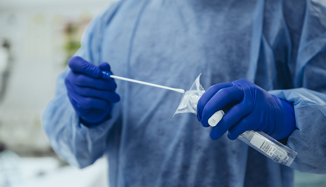 Técnico médico sostiene un tubo de ensayo y un hisopo para una prueba de covid-19