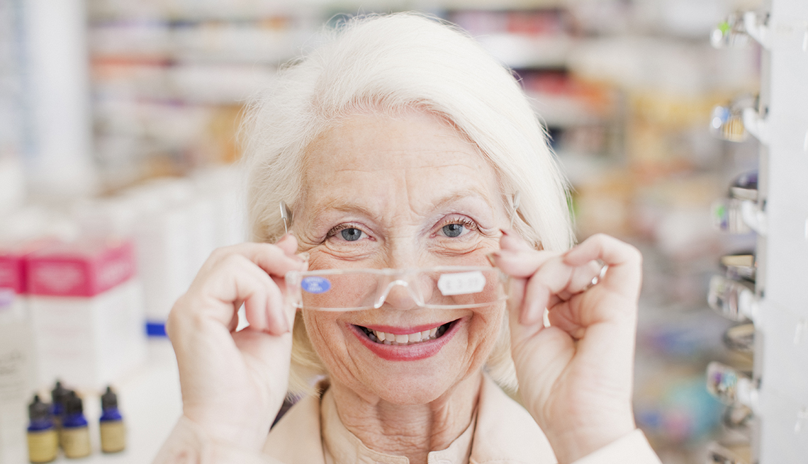 Woman trying on reading glasses at the drugstore.