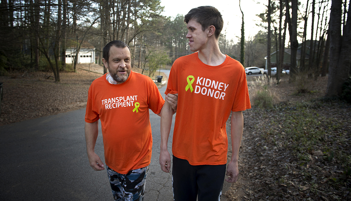 Father and son walking arm in arm, father's t-shirt says transplant recipient, son's t-shirt says kidney donor.
