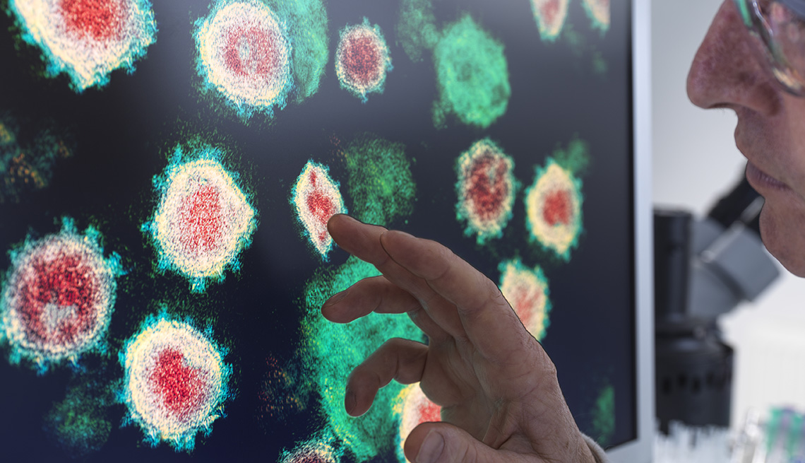 researcher looks at computer screen with images of viruses