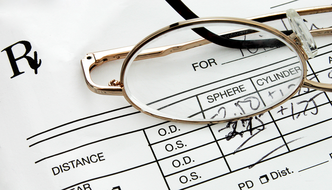 Close up of a pair of eyeglasses sitting on top of an eyeglass prescription.