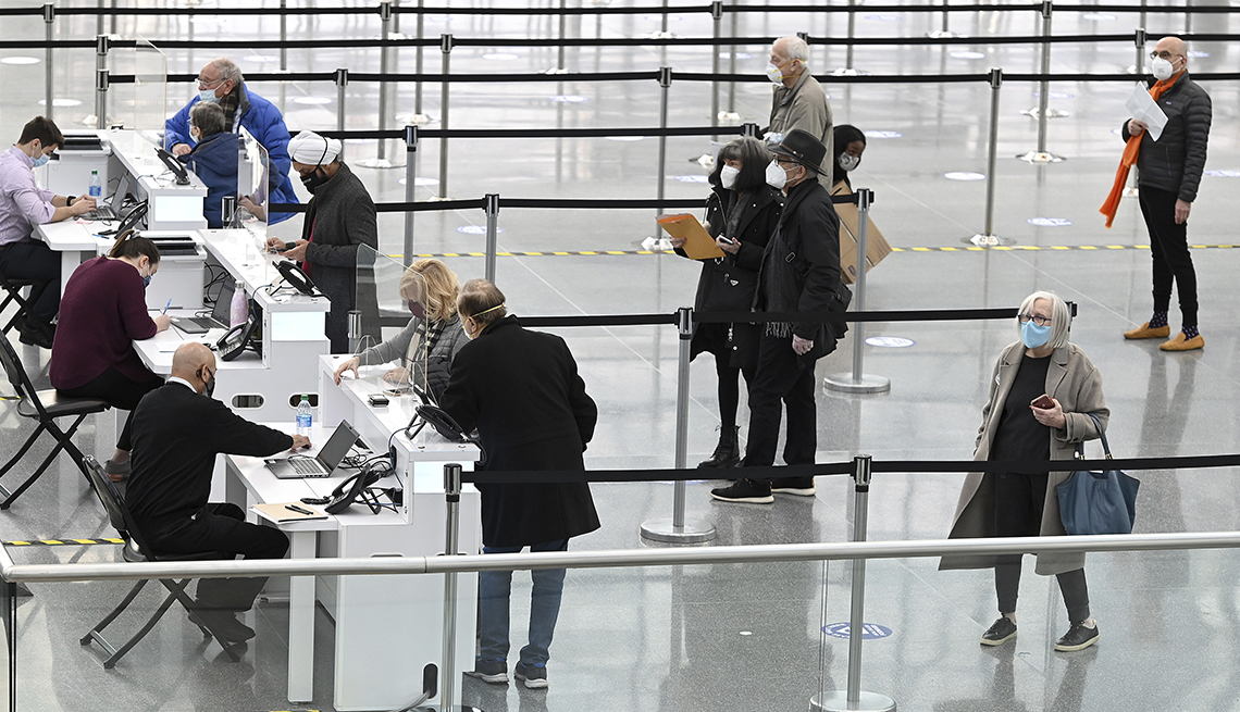 item 1 of Gallery image - Personas, guardando distancia, hacen fila en un aeropuerto