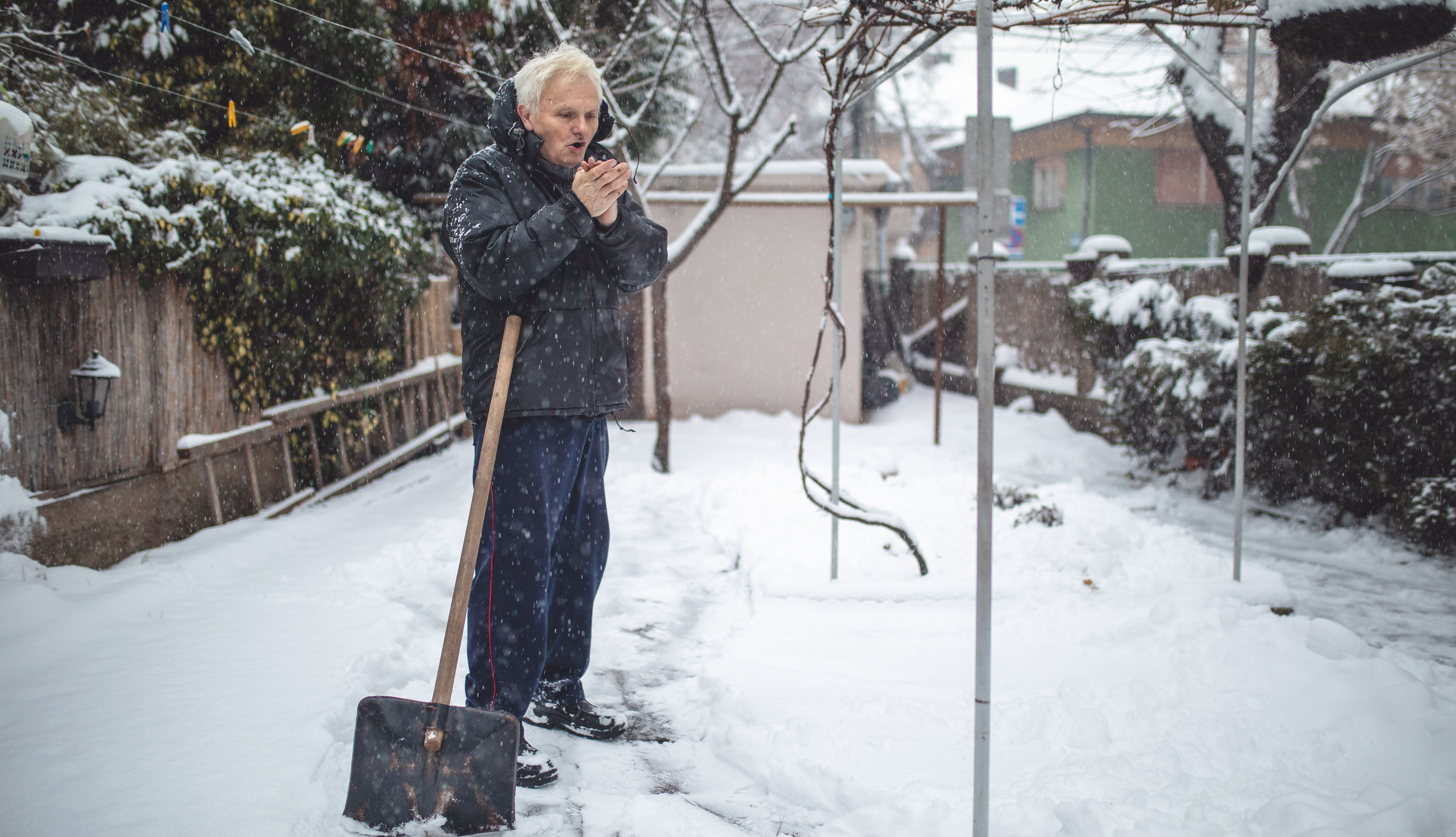 Un hombre adulto mayor saca nieve con una pala