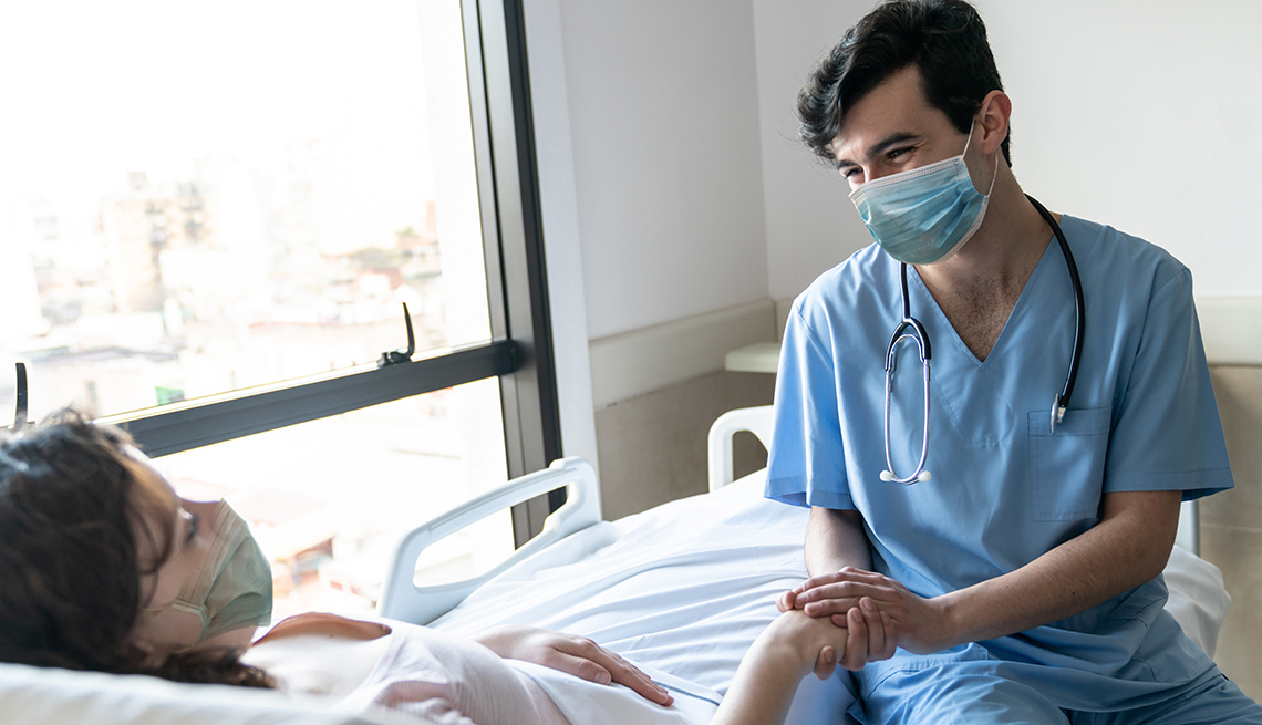 Nurse comforting patient, both wearing face masks