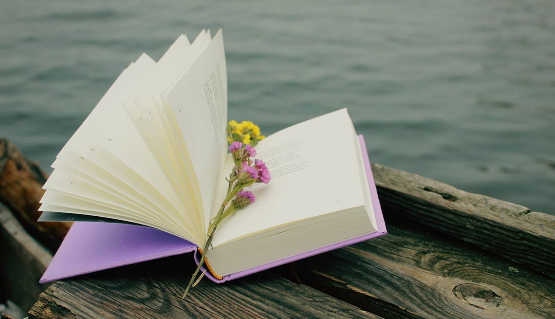 A book of poetry with flowers as a bookmark, with water in the background