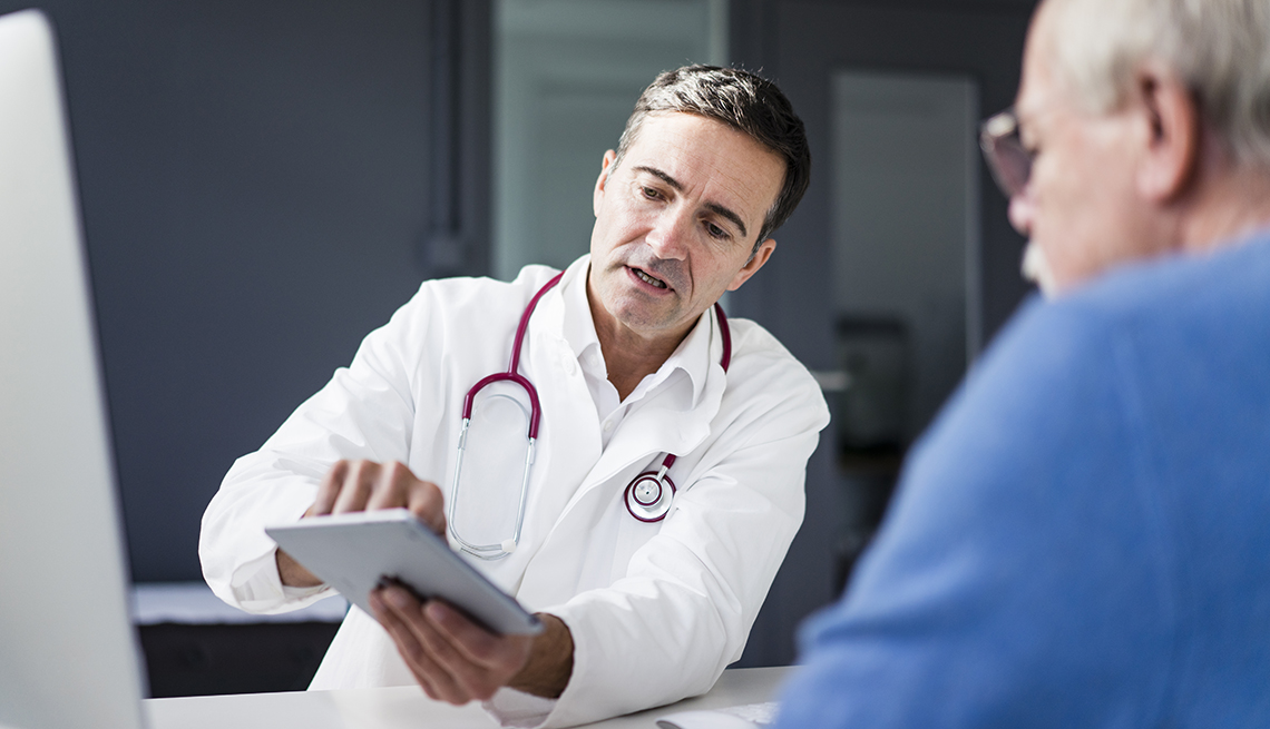 Un médico le muestra información en una tableta a un paciente