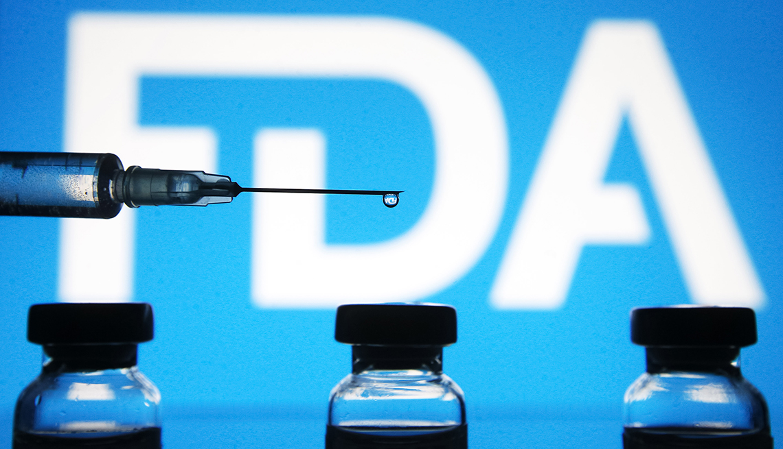 Ilustración de una jeringuilla, tres frascos de vacuna y al fondo dice FDA