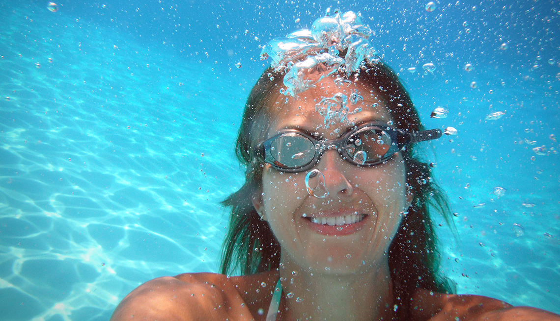 woman under water in a pool, wearing goggles