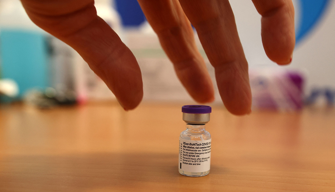 Una mano agarrando un vial de una vacuna contra la COVID