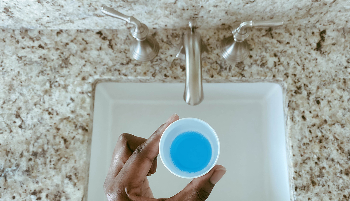 woman's hand holding a cup of mouth wash.