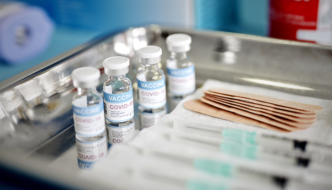 Vials and syringes with COVID-19 vaccine are displayed on a tray