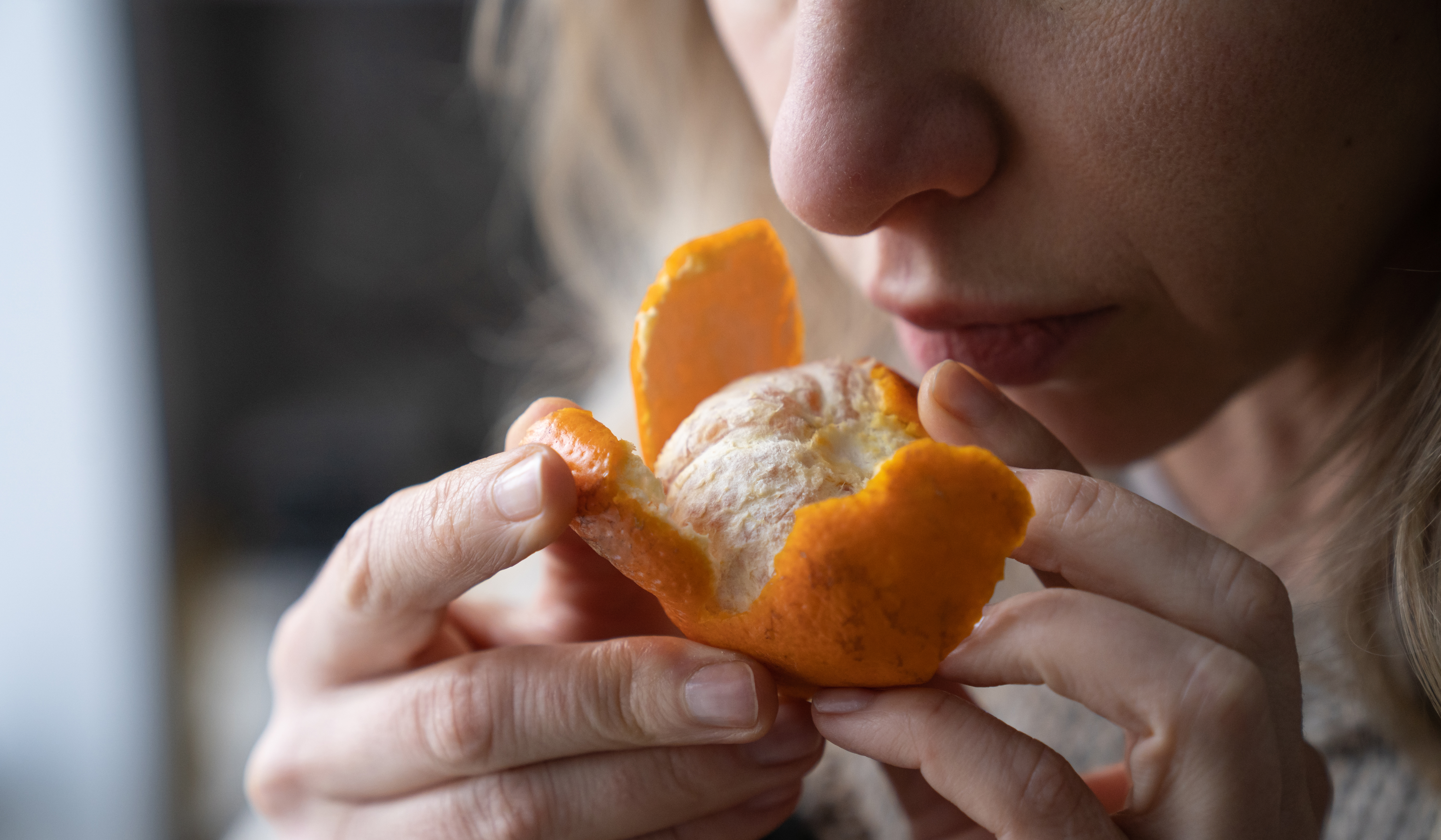 Una mujer con pérdida de olfato intenta oler una mandarina