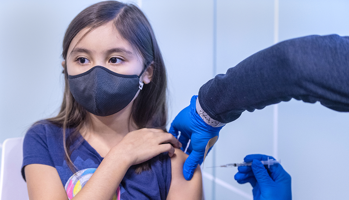 A nine year old girl holds the sleeve of her top as she receives the COVID-19 vaccine.