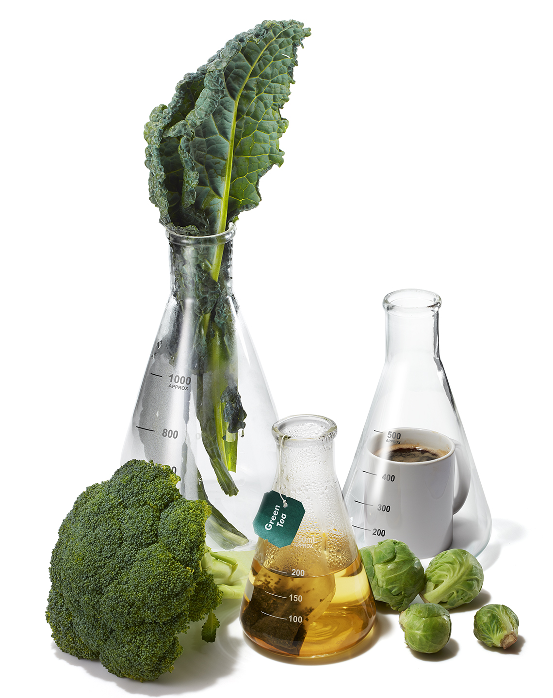 kale brussels sprouts broccoli green tea and coffee are placed inside and around scientific beakers and flasks to symbolize research