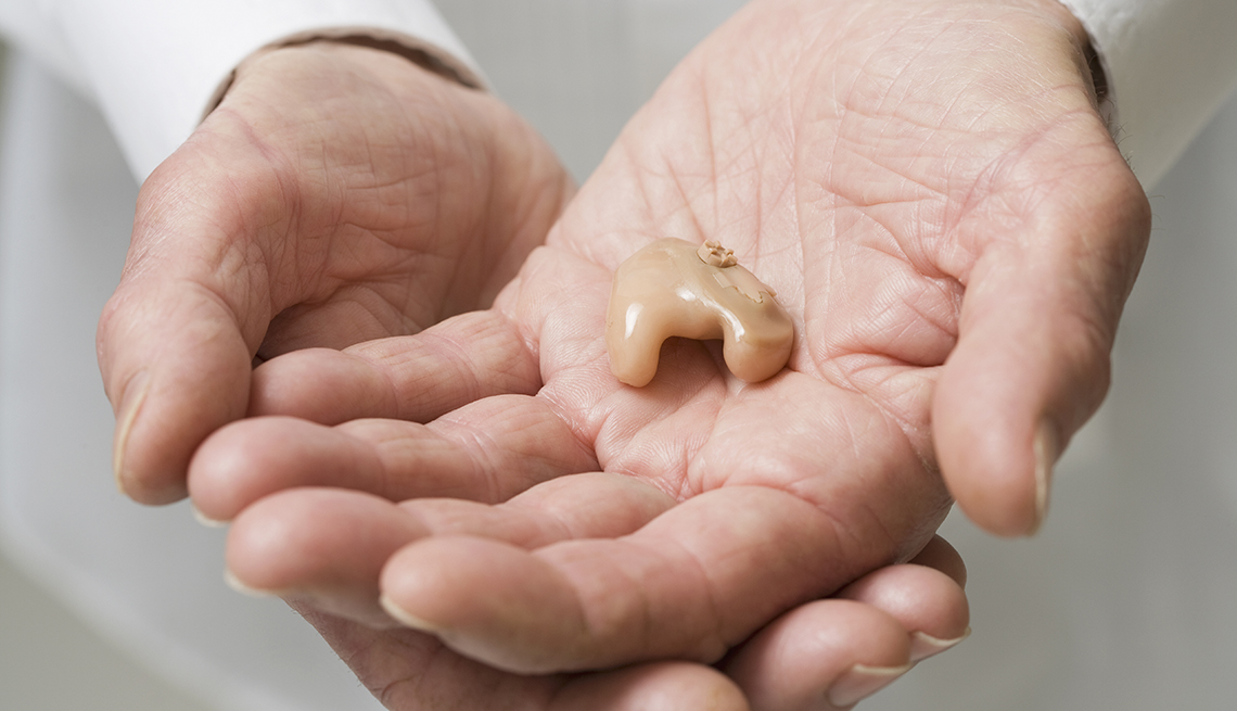 doctor's hands holding hearing aid