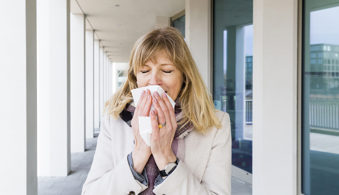 woman about to sneeze into a tissue, she's outside of an office building