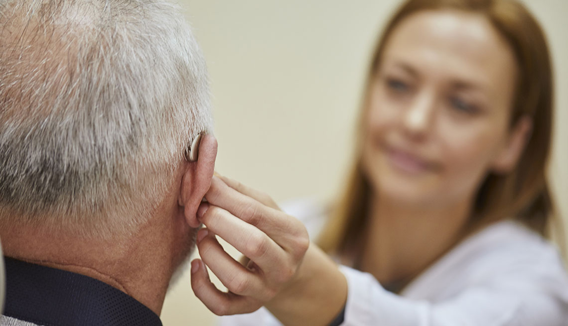 Una doctora le coloca un audífono a su paciente