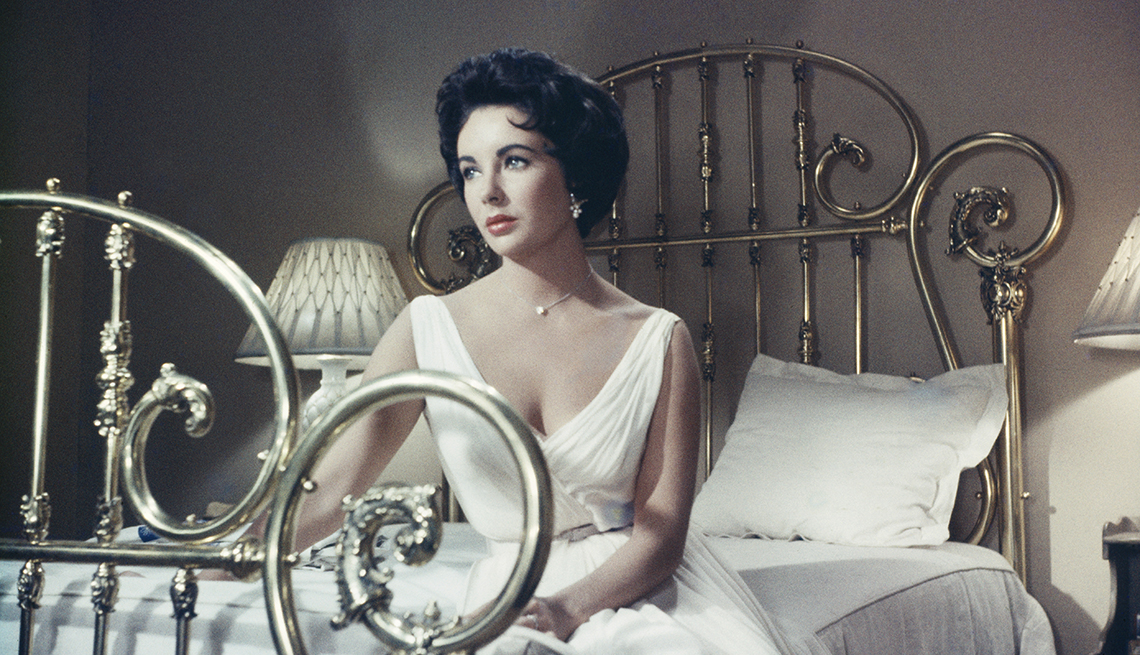 Actress Elizabeth Taylor sitting on a bed in the MGM film, 'Cat On A Hot Tin Roof', 1958.