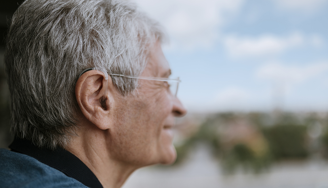 Un hombre, visto de perfil, usa audífonos para escuchar mejor