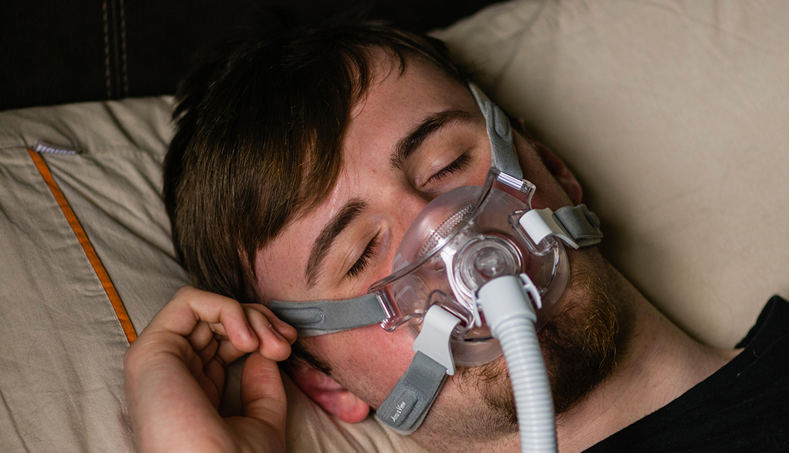 man in bed at night using a Philips Respironics System One CPAP machine