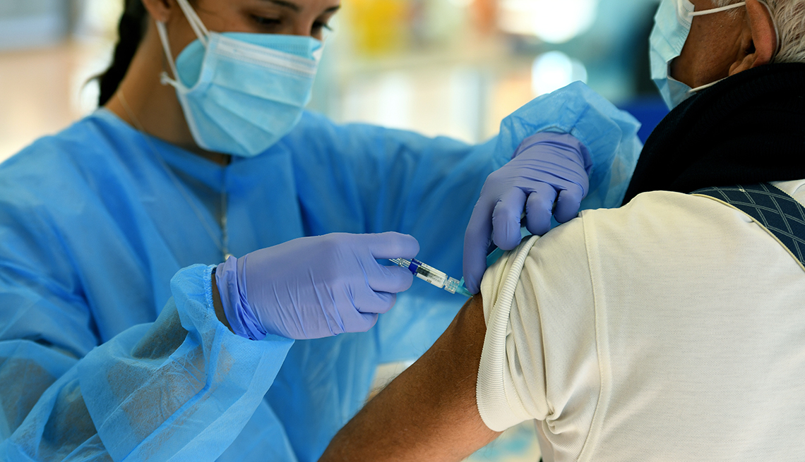 nurse prepares to administer a flu vaccination to a man