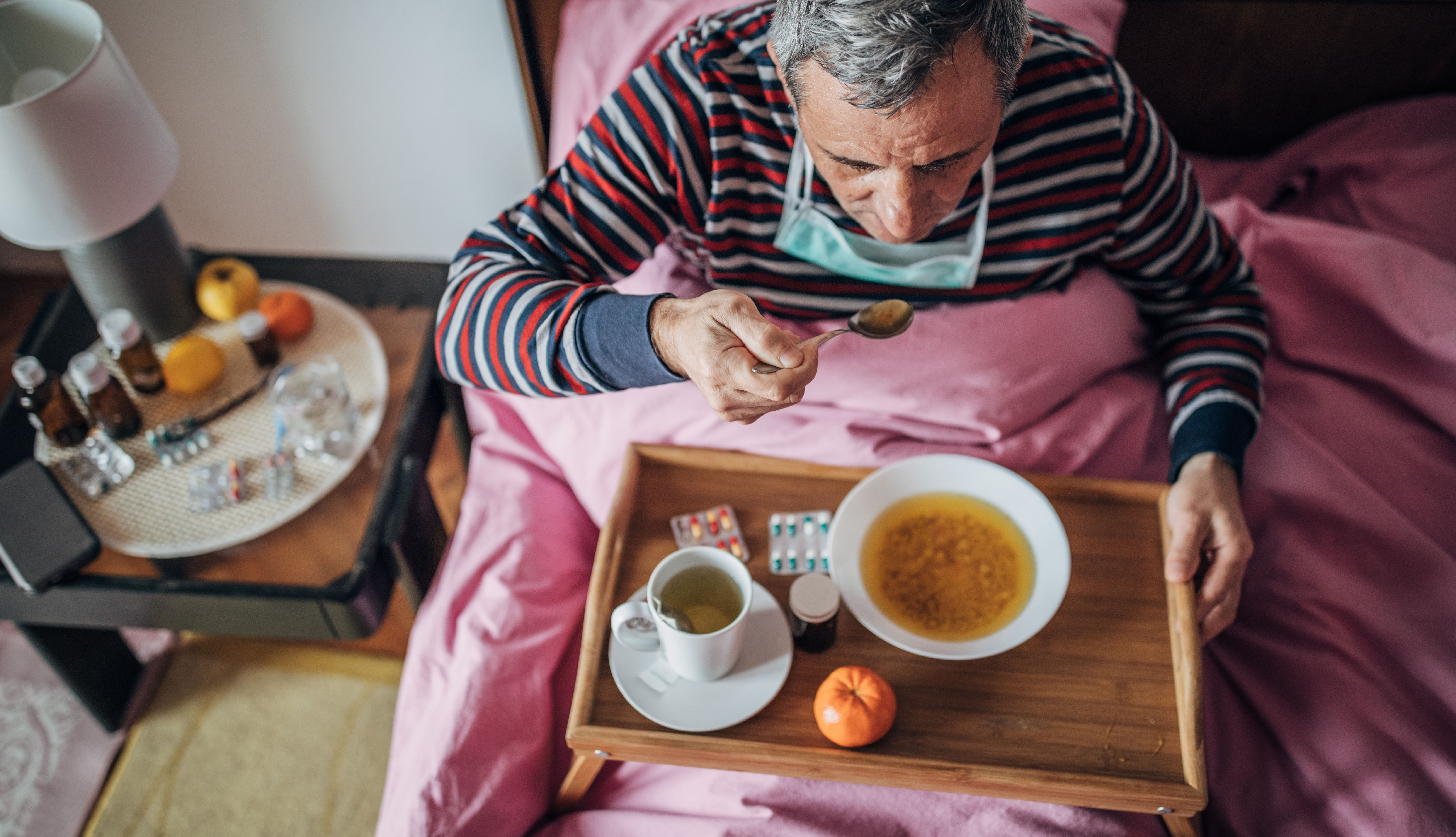 man eating chicken soup in bed