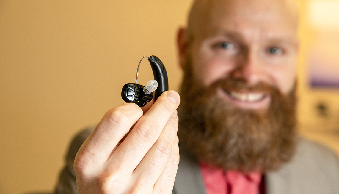 Un hombre sostiene un audífono de venta libre para la pérdida auditiva