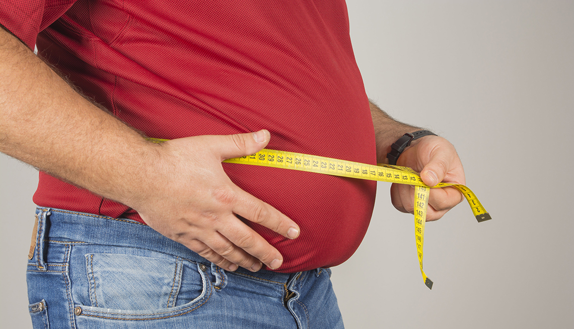Hombre con una cinta de medir mide la circunferencia de su abdomen