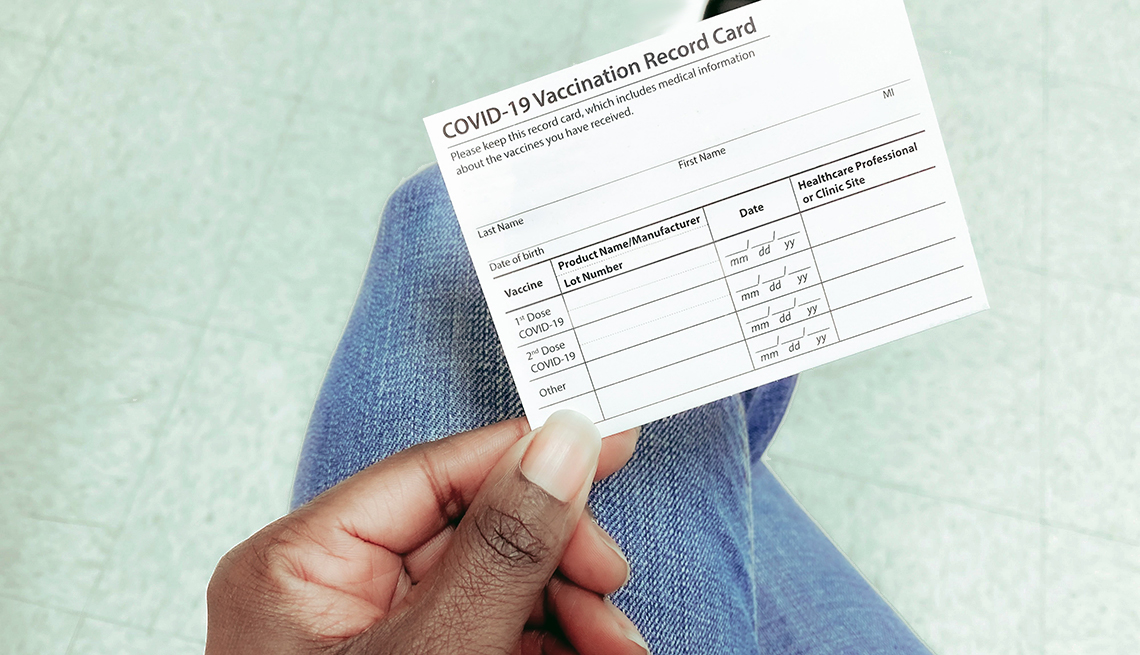 High angle view of person's hand holding COVID-19 vaccination record card