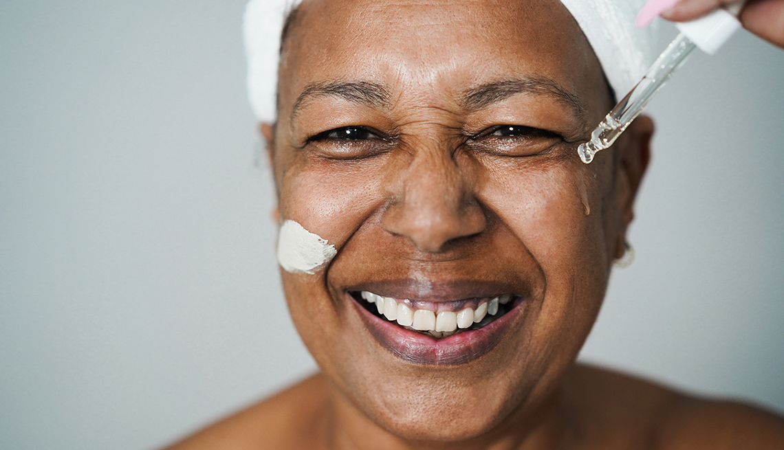 Una mujer mayor se aplica un suero a su rostro.