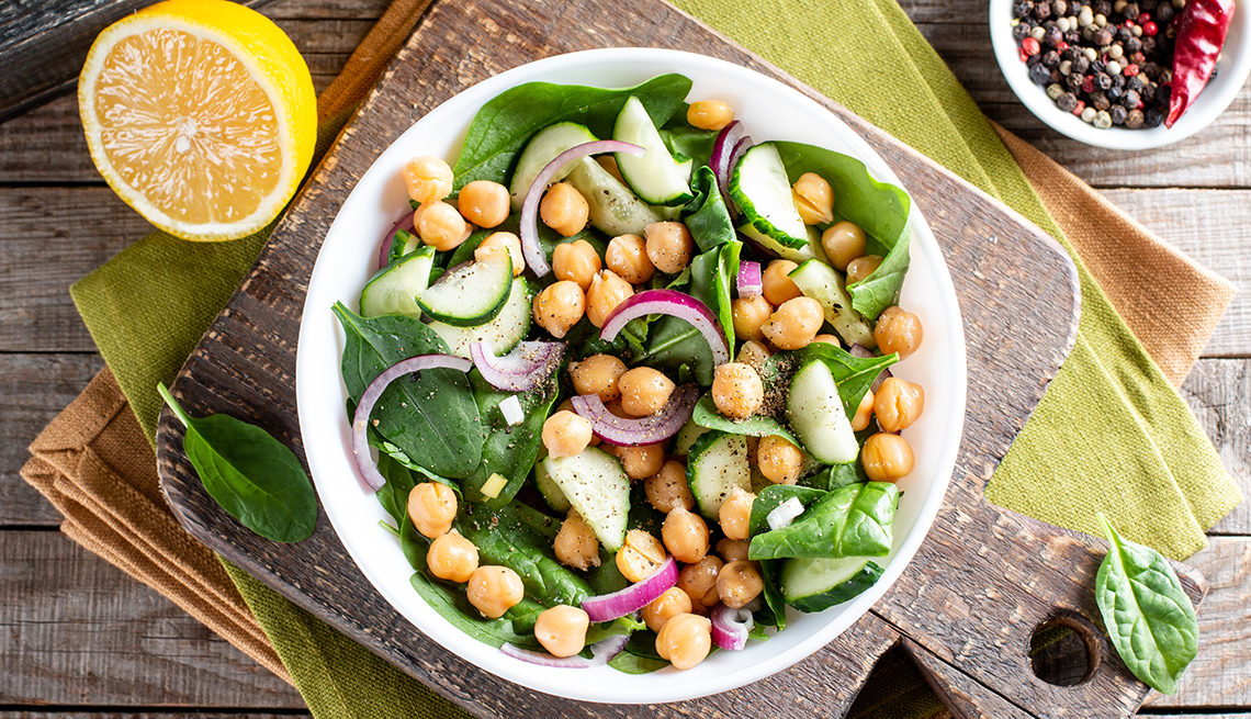 green vegetable salad with chickpea, spinach, cucumber, red onions, and greens on a wooden table