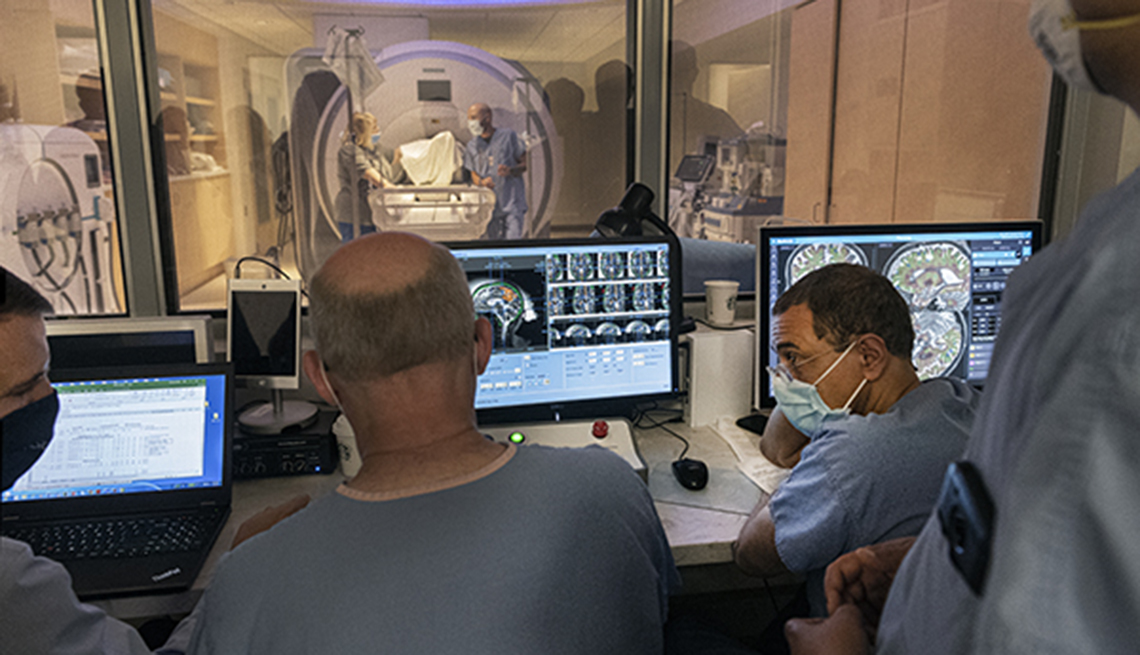four doctors analyzing a brain scan while patient is getting an ultrasound scan