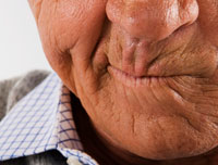 Are your medications making you itchy? A senior man grimaces in frustration.