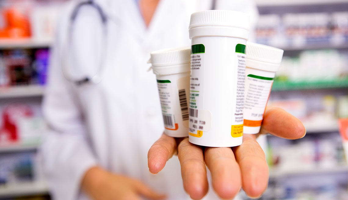 Empleado de farmacia con varios frascos de medicamentos en su mano