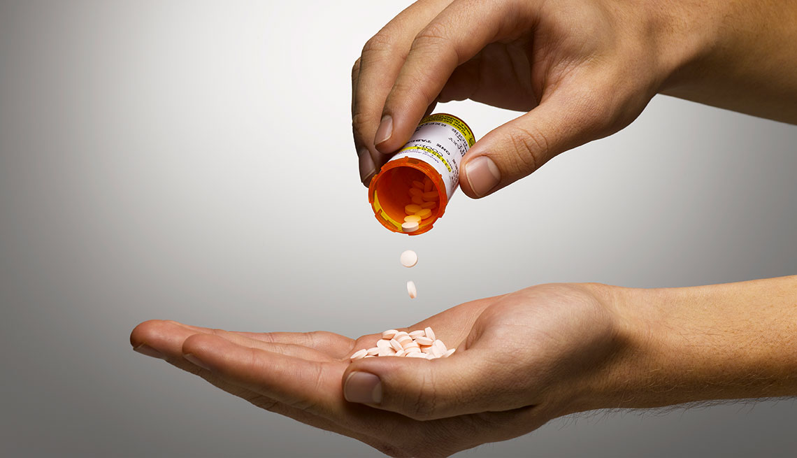 Close up photo of a person pouring prescription pills into hand